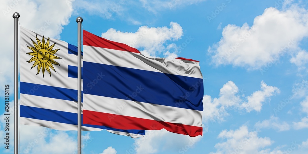 Uruguay and Thailand flag waving in the wind against white cloudy blue sky together. Diplomacy concept, international relations.
