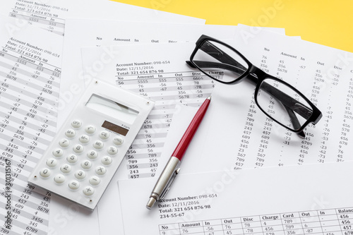 Taxes calculation concept. Financial documents, calculator, glasses on yellow background