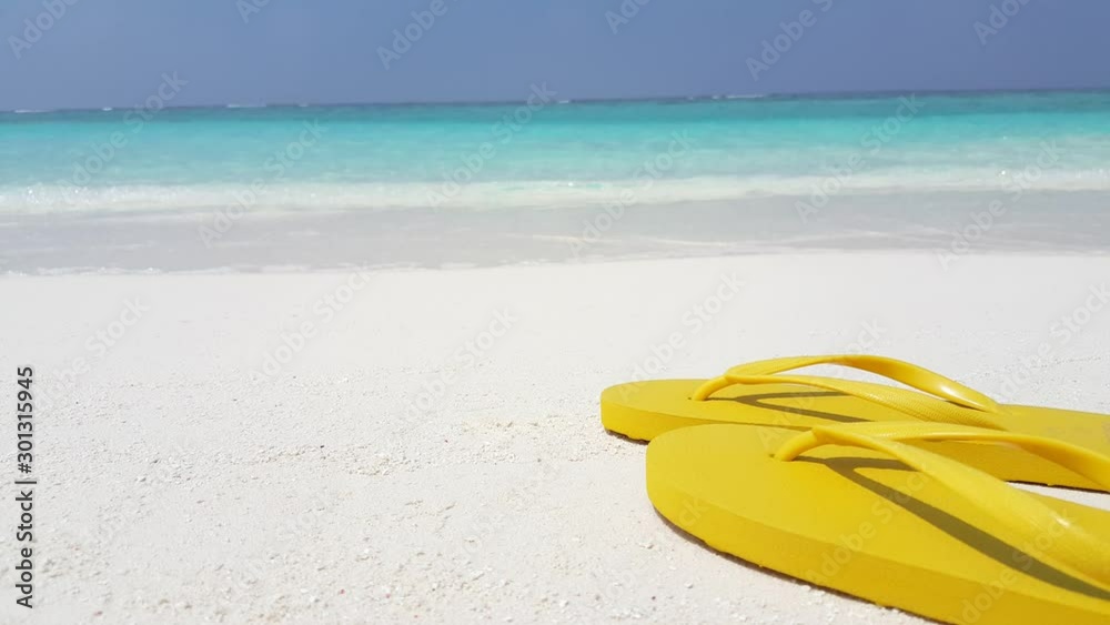 Pair of Yellow Flip Flop Slippers At the Seashore With Turquoise Sea and Cloudly Sky At the background in Panama - Closed Shot Pair of Yellow Flip Flop Slippers At the Seashore With Turquoise Sea and Cloudly Sky At the background in Panama - Closed Shot