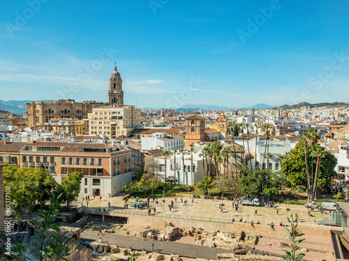 View of the roman theatre of Malaga, Spain on a sunny day. The Cathedral and Picasso Museum in the background.