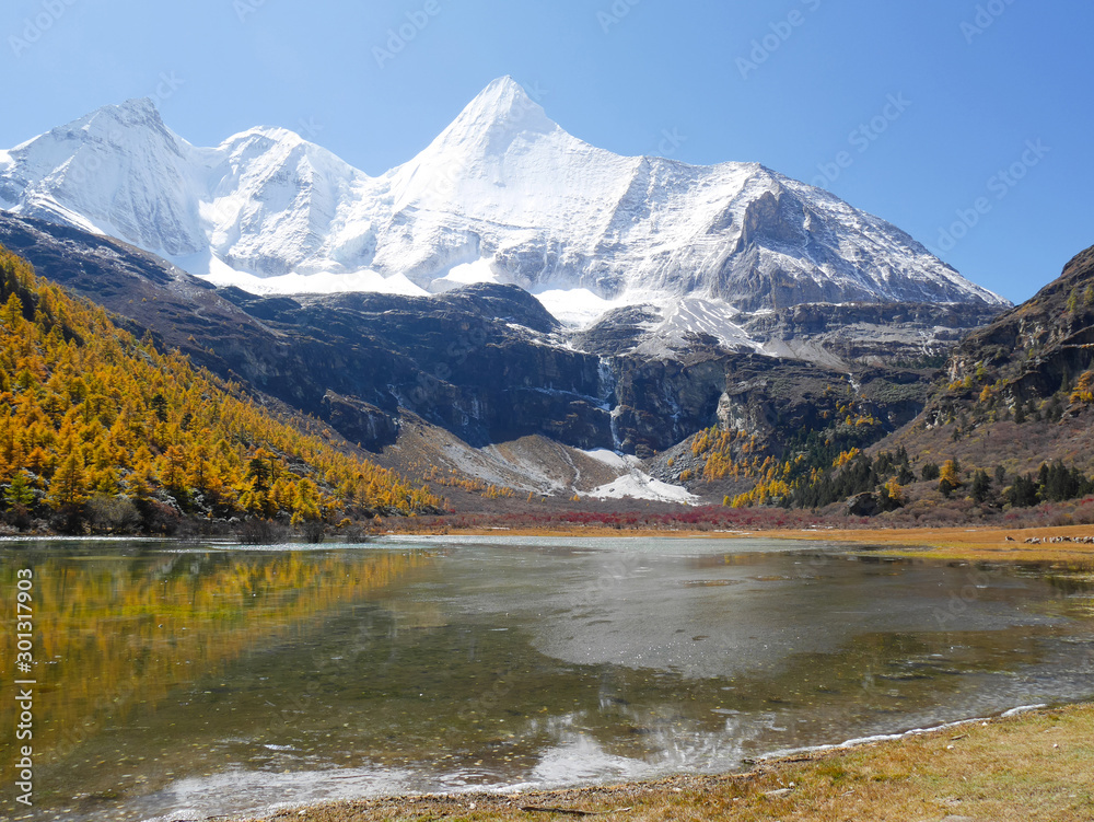 View of snow covered mountain peaks, lake and bharals or blue sheep