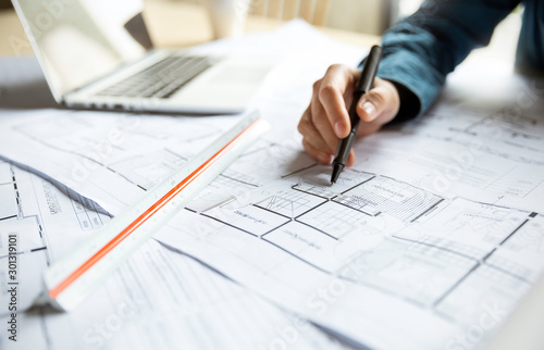 Close up woman hand working of Architect sketching project on blueprint at site construction work. Concept of architect, engineer in the office desk construction project photo