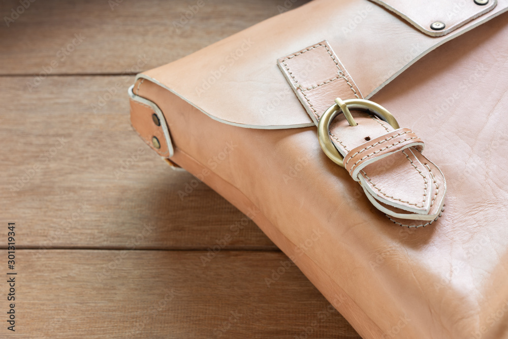 detail of genuine leather bag with fastened buckle strap on wooden table, close up. fashion concept. detail of genuine leather bag with fastened buckle strap on wooden table, close up. fashion concept.