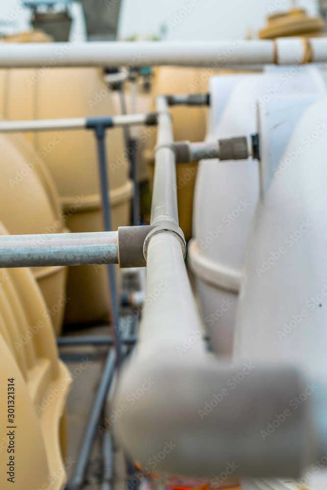 Fototapeta premium closeup of a joint of PVC water supply pipe connected to the huge water tanks 