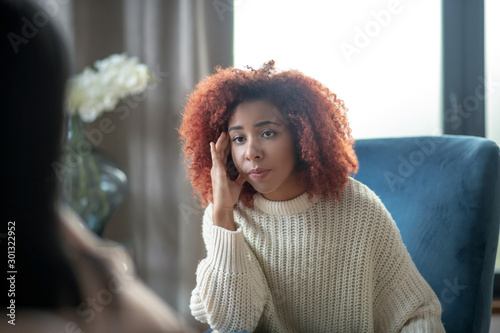 Young woman feeling concerned while having psychoanalysis