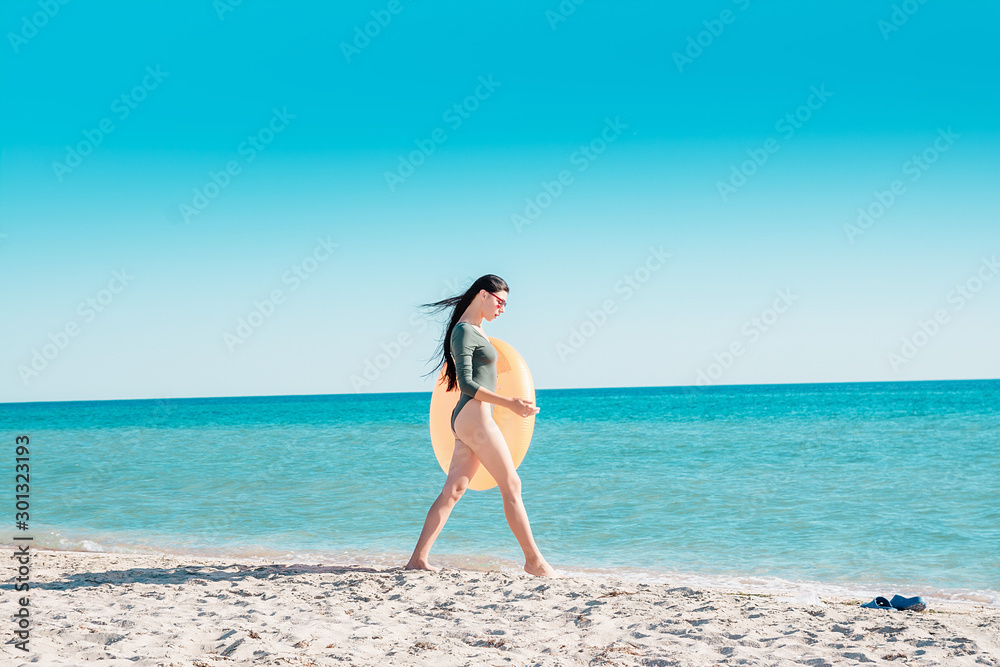 Portrait of a girl in pink glasses and with an orange rubber ring on the beach. Portrait of a girl in pink glasses and with an orange rubber ring on the beach.