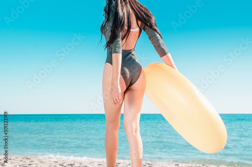 Portrait of a girl in pink glasses and with an orange rubber ring on the beach.