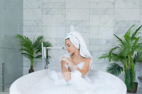 Billede på lærred Beautiful young woman  in warm bathtub with foam and  washes