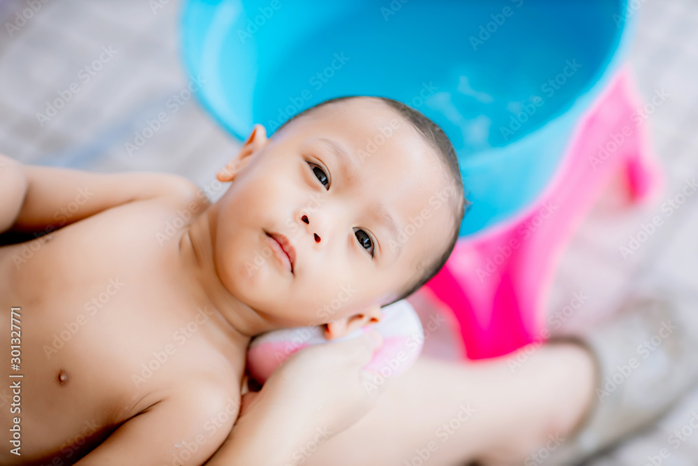 Bath time for a cute little newborn baby. Newborn baby boy take a bath. Mom cleaning her baby hair with sponge.Asian new born having a bath by mother. Bath time for a cute little newborn baby. Newborn baby boy take a bath. Mom cleaning her baby hair with sponge.Asian new born having a bath by mother.