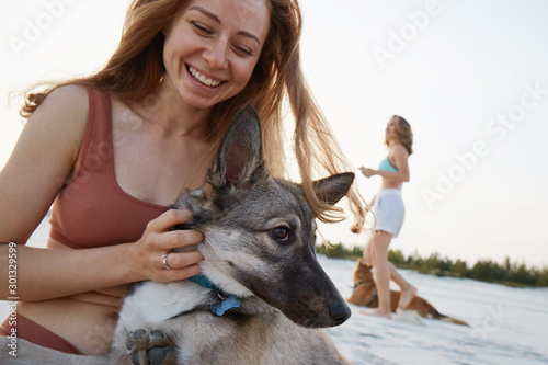 A girl hugging her dog on the beach in sunset laughing photo