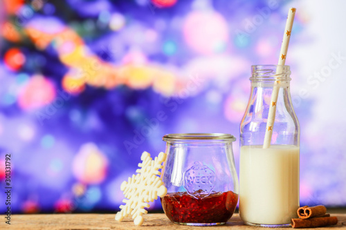 glass of mulled wine and candle on wooden background