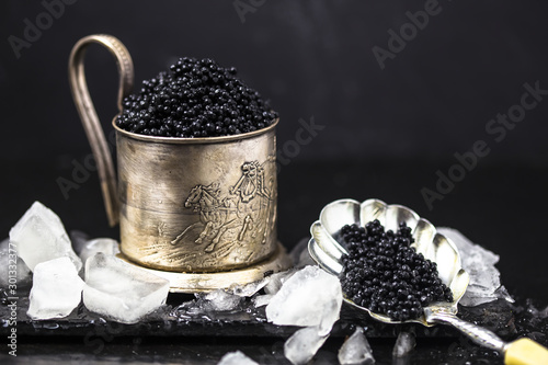 Принти на полотні black caviar in  mug  with black caviar spoon on dark moss background