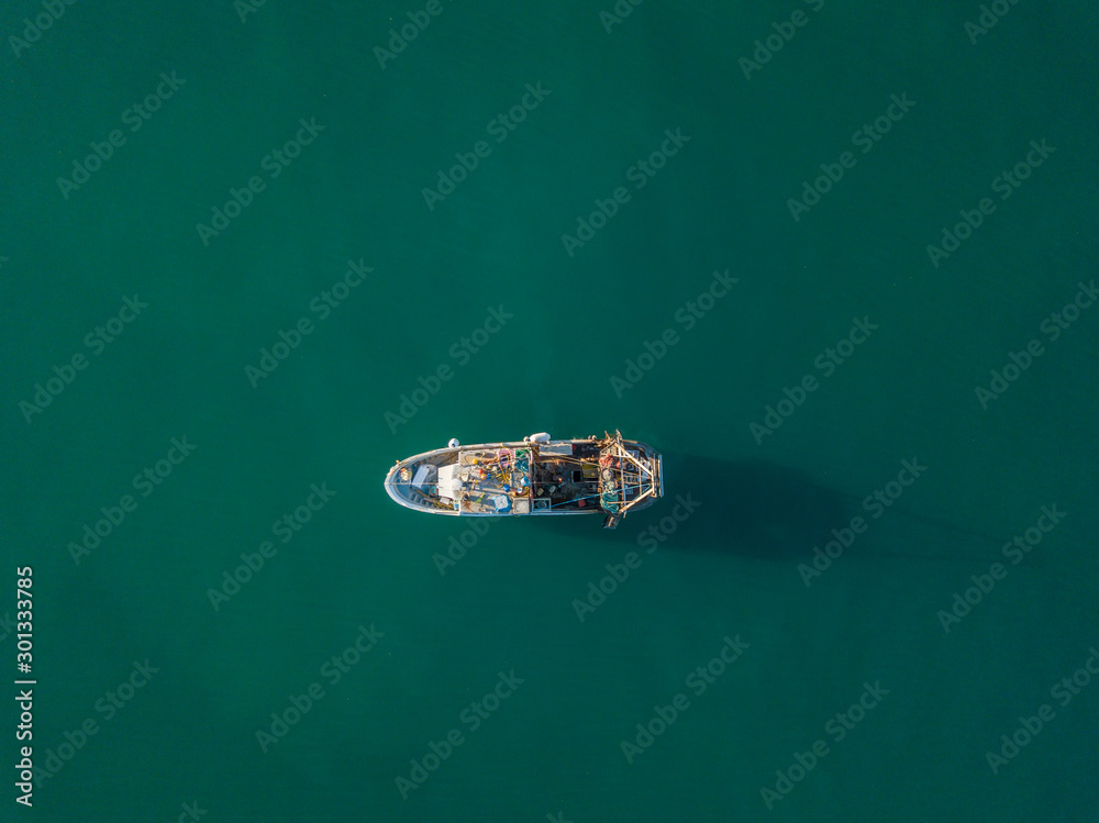 Aerial view of fishing boat anchored on ocean. Peaceful scene on water. Concept of traditional fishing in Europe. Aerial view of fishing boat anchored on ocean. Peaceful scene on water. Concept of traditional fishing in Europe.