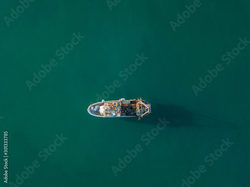 Aerial view of fishing boat anchored on ocean. Peaceful scene on water. Concept of traditional fishing in Europe.