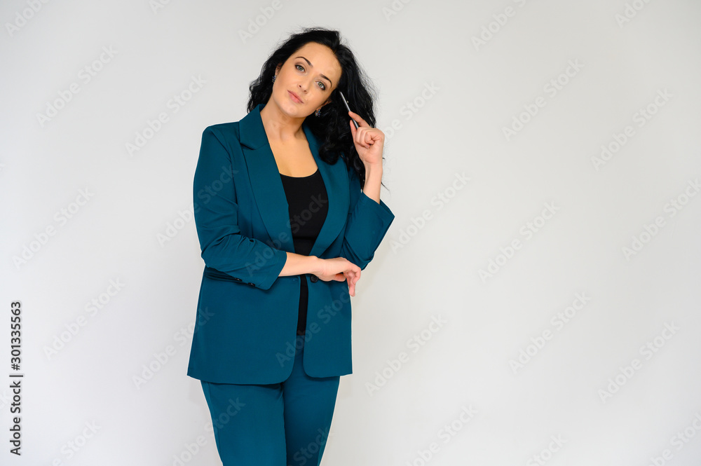 Portrait of a pretty brunette woman with long curly hair on a white background in a business suit. He stands in front of the camera, smiles, talks in various poses. Portrait of a pretty brunette woman with long curly hair on a white background in a business suit. He stands in front of the camera, smiles, talks in various poses.