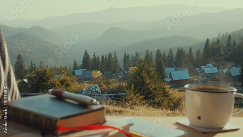 Van Life Panorama with steaming coffee plus notebook and cellphone on van table in front of mountain panorama