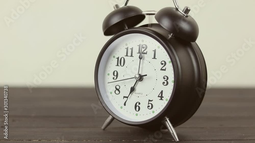 vintage alarm clock on wooden table with cement wall