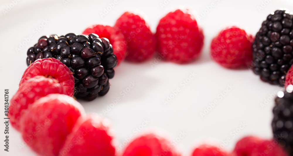 raspberries and blackberries laid out on a white plate in circle raspberries and blackberries laid out on a white plate in circle