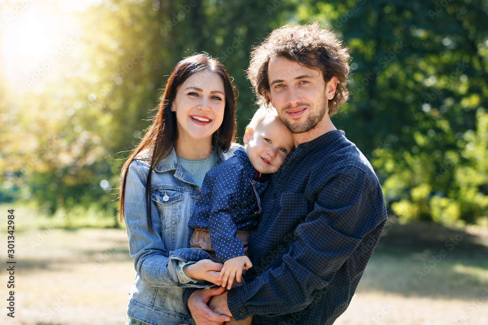 Family life. Portrait of parents and their son on the background of nature. Walk in park.