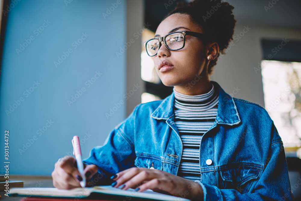 Contemplative female student in optical eyewear for vision correction thoughtful looking away and thinking about idea for essay during time for autodidact, pensive teenager learning on publicity area - obrazy, fototapety, plakaty 