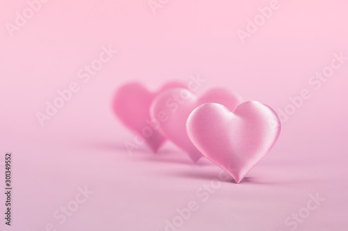 Pink silk heart on a pink background is standing in line. The concept of minimalism. Place for text. Pastel colors .