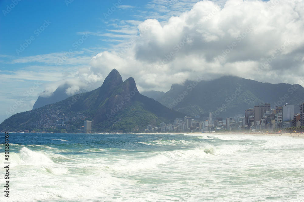 Scenic misty view of Two Brothers Mountain with big winter swells surging onto Ipanema Beach in Rio de Janeiro, Brazil