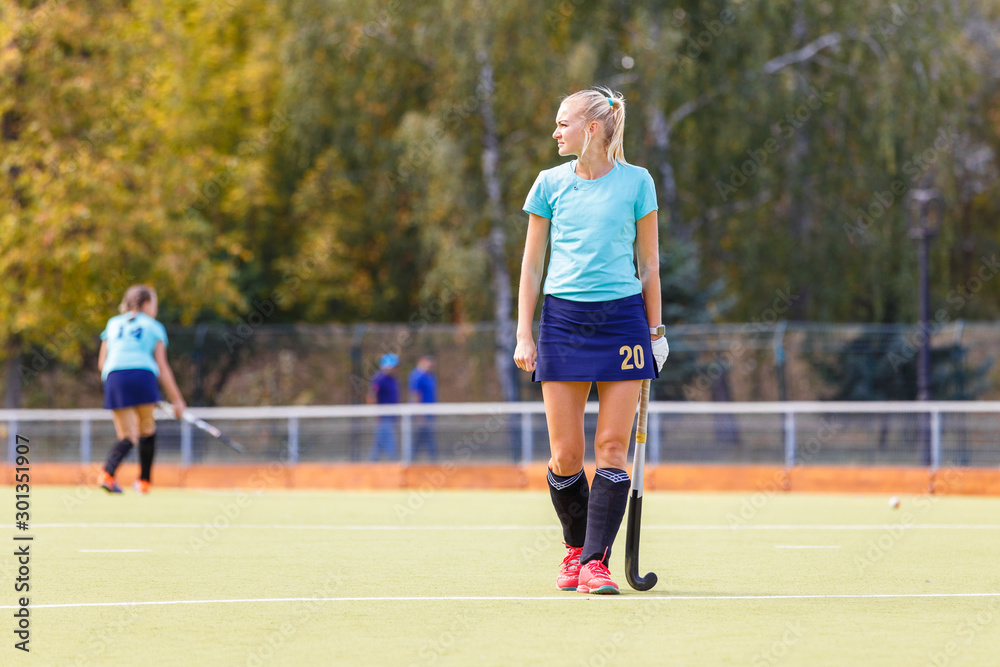 Young female hockey player with stick on the field