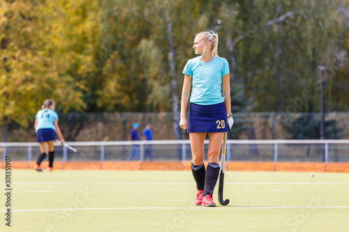 Young female hockey player with stick on the field