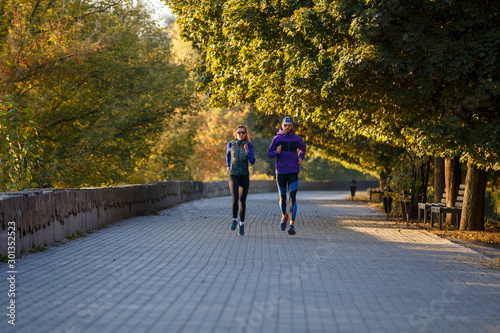 Young couple running in autumn park in the morning