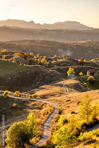 Incredable sunset in the durmitor national park in Montenegro during autumn season with golden fall colors on the trees with mountain huts scattered in the hills photo