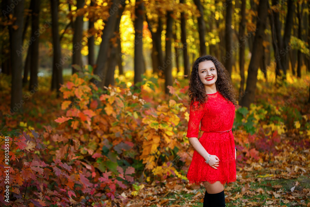 girl with curls in a red dress in the autumn forest girl with curls in a red dress in the autumn forest