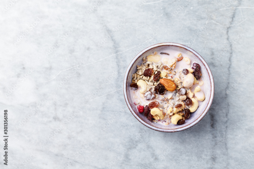 Bowl of granola with yogurt, nuts, raisins, cranberries and chia seeds. Concept for a tasty and healthy meal. Stone background. Top view. Copy space. Bowl of granola with yogurt, nuts, raisins, cranberries and chia seeds. Concept for a tasty and healthy meal. Stone background. Top view. Copy space.