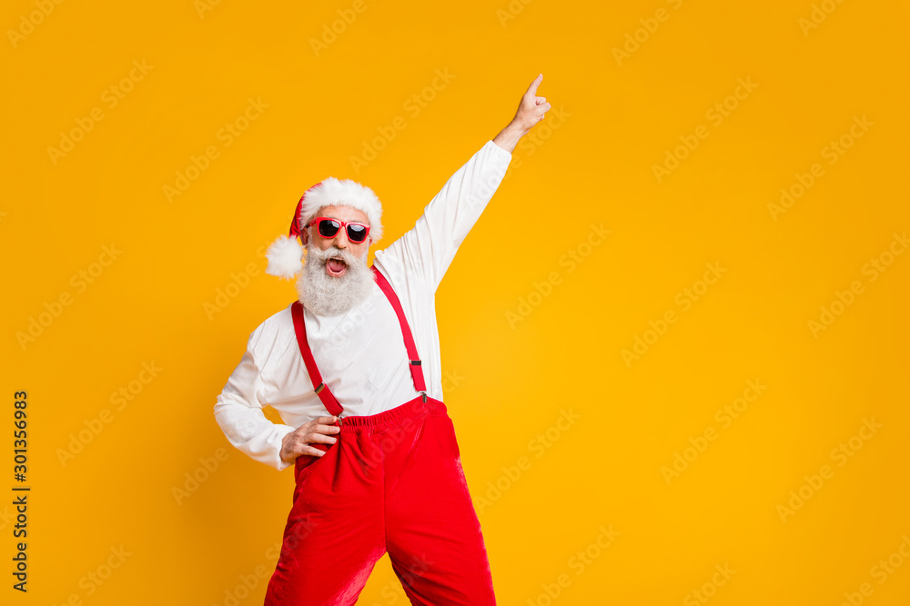 Christmas party hard. Portrait of crazy funny santa claus hipster in red hat enjoy x-mas noel celebration dance raise index finger wear shirt suspenders isolated yellow color background - obrazy, fototapety, plakaty 