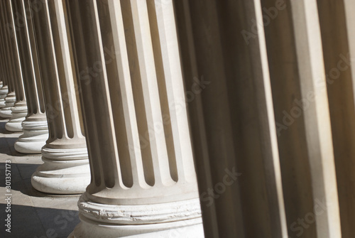 Dramatic sunlit down a colonnade of fluted columns with shadowy architectural texture