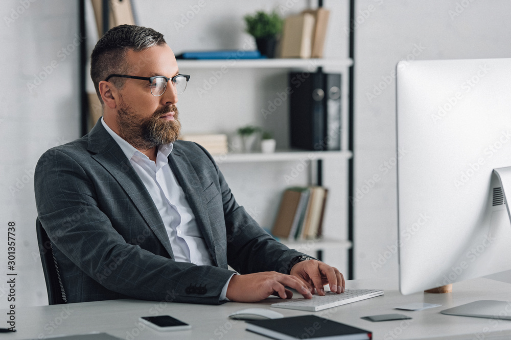 © LIGHTFIELD STUDIOS - handsome businessman in formal wear and glasses using computer