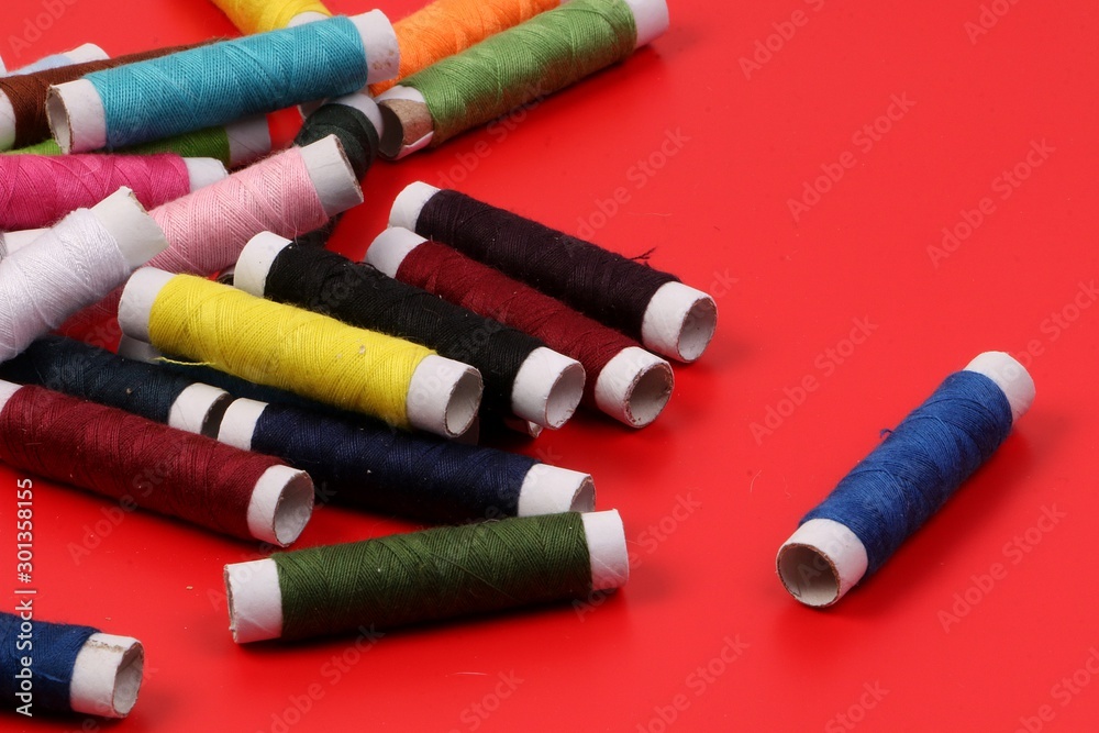 pile of colorful sewing rolls lie on a red background pile of colorful sewing rolls lie on a red background