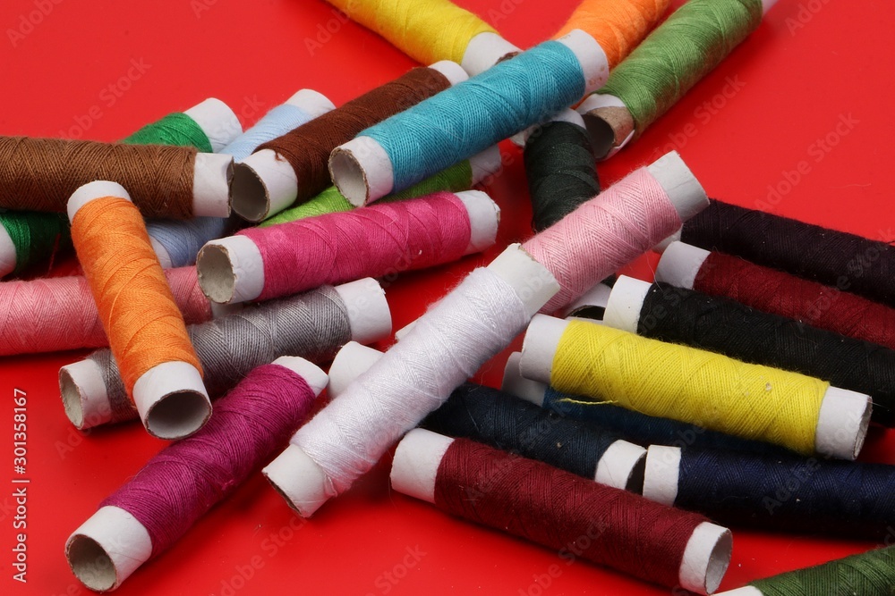 pile of colorful sewing rolls lie on a red background pile of colorful sewing rolls lie on a red background