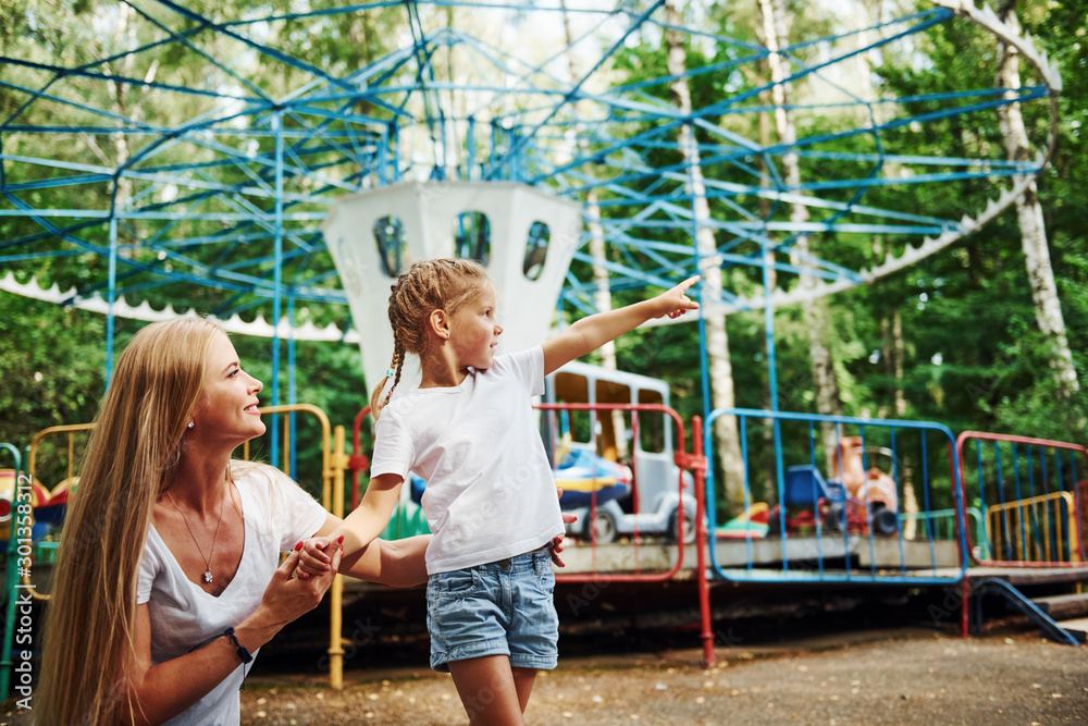 Loving each other. Cheerful little girl her mother have a good time in the park together near attractions