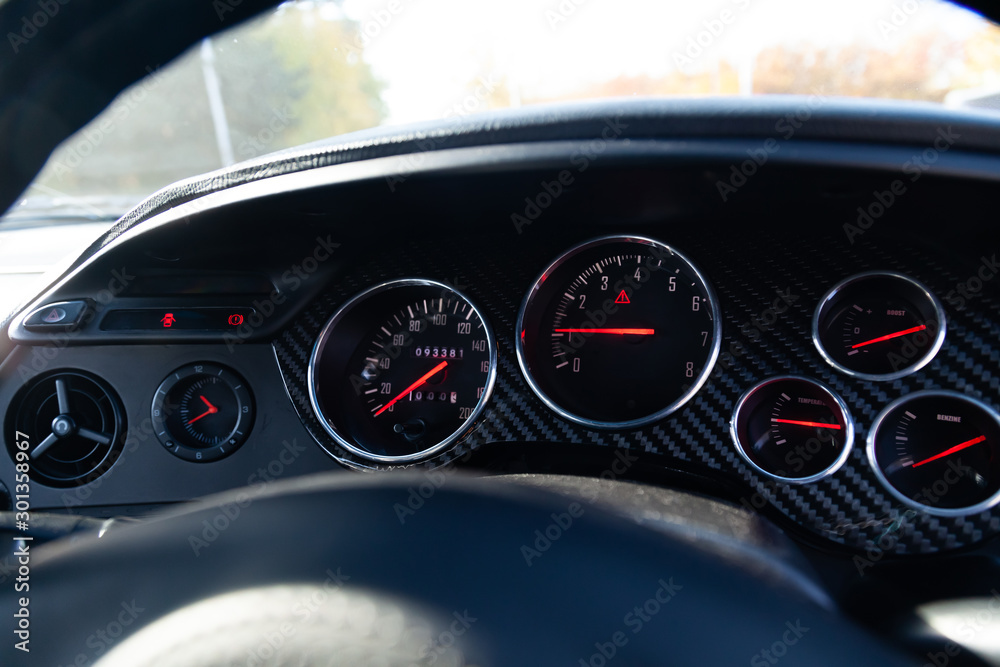 The dashboard of the car with red arrows and carbom trim, a speedometer, tachometer and other tools to monitor the condition of the vehicle in modern style on black isolated background