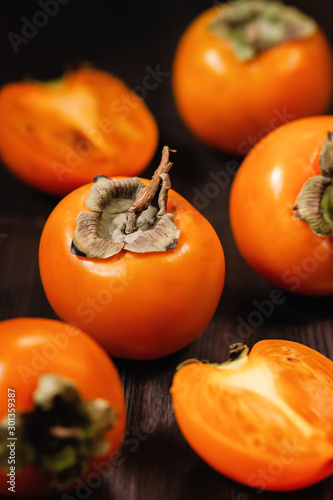 Sweet, ripe persimmon fruit close up on dark background. Food still life with tropical fruit in rustic style, copy space. Healthy eating concept