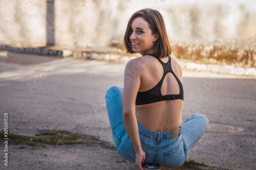 Young woman sitting on her skate in an old industrial street