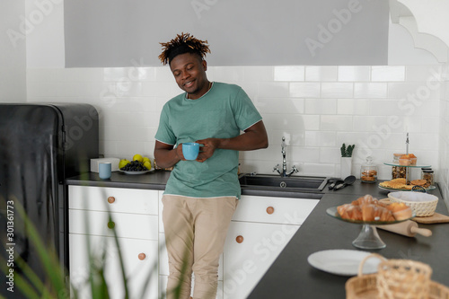 Cheerful Afro American man standing in the kitchen