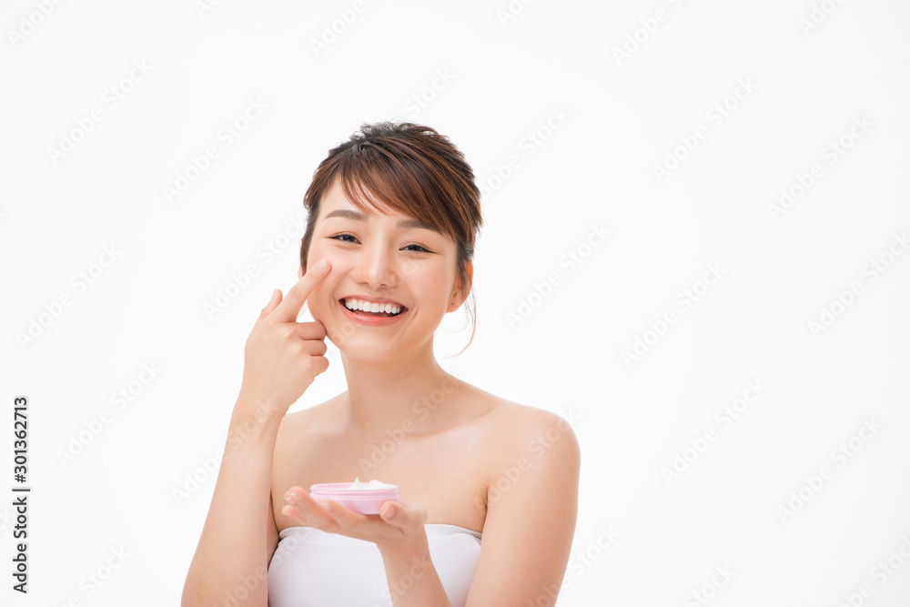 Beauty concept. Asian girl is applying cream on her face. Beauty concept. Asian girl is applying cream on her face.