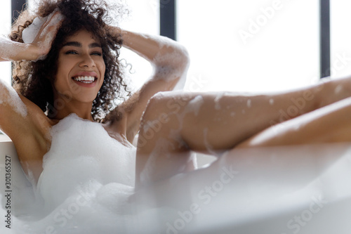 Leinwand Poster Cheerful Afro American girl relaxing in bathtub