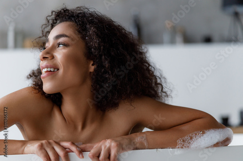 Charming Afro American lady taking bath and smiling