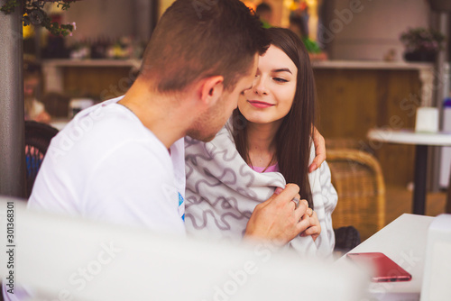 Couple in love sit in cafe outdoor, urban background.