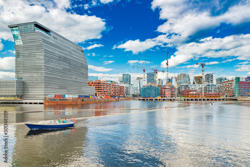 Cityscape of downtown Oslo with modern architecture, boat with a group of people and the blue sky with clouds, Norway
