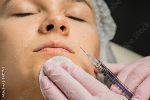 contour plastic. A cosmetologist injects a botulinum toxin to tighten and smooth out wrinkles on the skin of a female face.