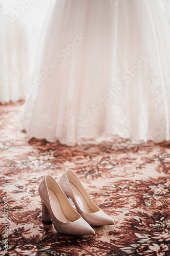 Pair of high heel shoes and white wedding dress