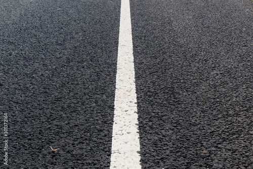 White solid line. Road marking on an asphalt road.